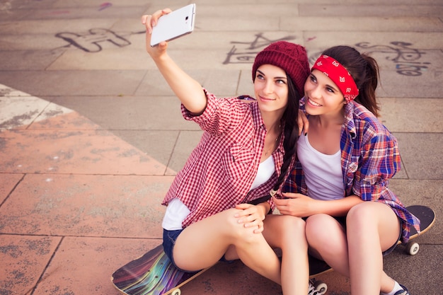 Two teenage hipster girls on skateboards