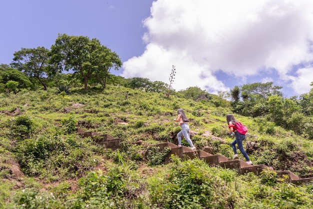 Two teenage women climbing a mountain by concrete stairs