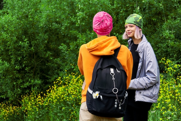 Two teenagers chatting outdoors on green foliage background