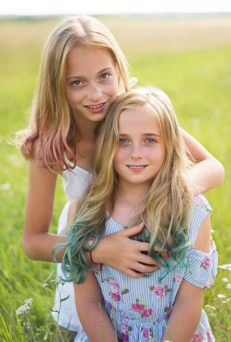 Two teenagers, hugging their sister, in the field in summer, warm days, colored hair