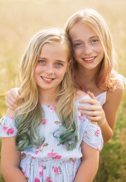 Photo two teenagers, hugging their sister, in the field in summer, warm days, colored hair