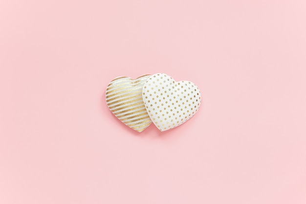 Two textile hearts with golden pattern on pink background, central composition, minimal style