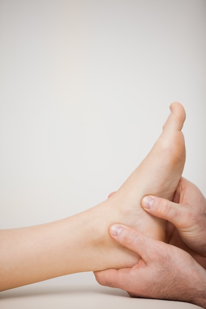 Two thumbs being placed on the side of a foot