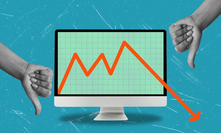 Photo two thumbs down on a computer screen showing a dropping graph