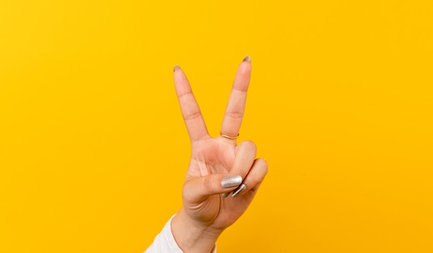 Photo two thumbs up, the girl's hand on the yellow background. show fight mutual encouragement