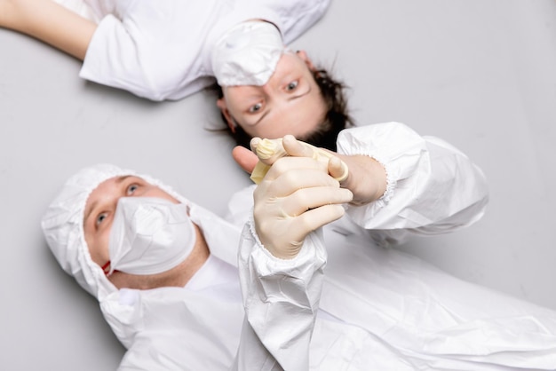 Two tired doctor male and female in a protective suit on the floor exhausted in the fight against a ...