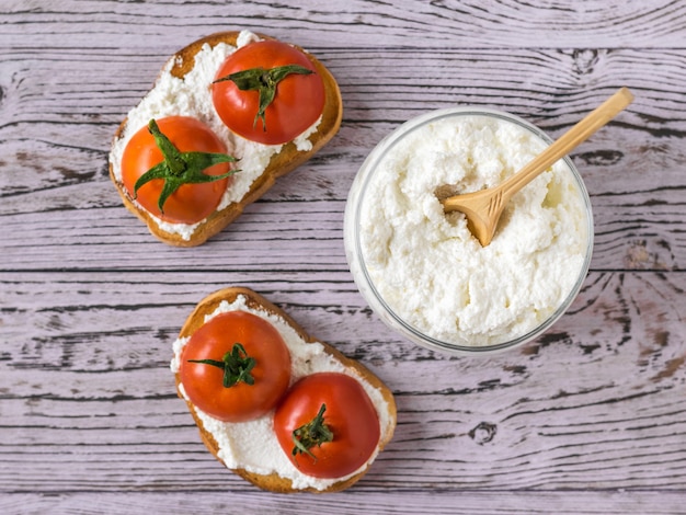 Two toast with tomatoes and cottage cheese on a wooden table.