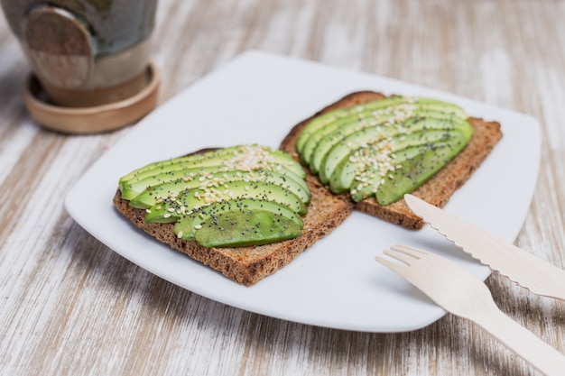 Two toasts with avocado on a wooden table