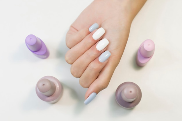 Two-tone manicure with blue and white nail polish and nail polish bottles