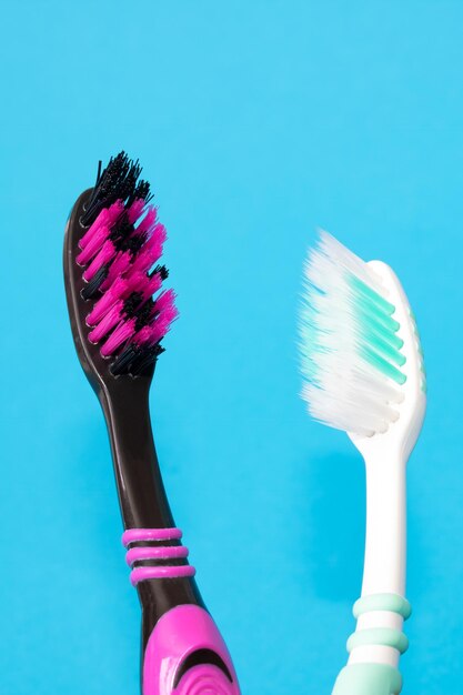 Two toothbrushes on a blue background closeup