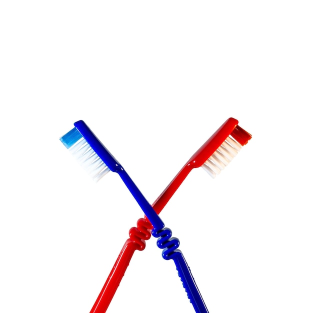 Photo two toothbrushes crossed on a white background blue and red toothbrushes