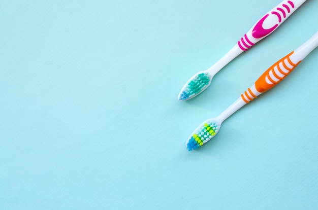 Two toothbrushes lie on a pastel blue background. top view, flat lay. minimal concept