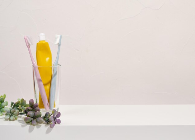 Two toothbrushes and toothpaste stand in a glass Copy space for text Concept of dental health and dental care