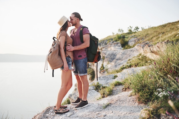 Photo two tourist male and woman with backpacks stand to the top of the mountain and enjoying sunrise. travel lifestyle adventure vacations concept