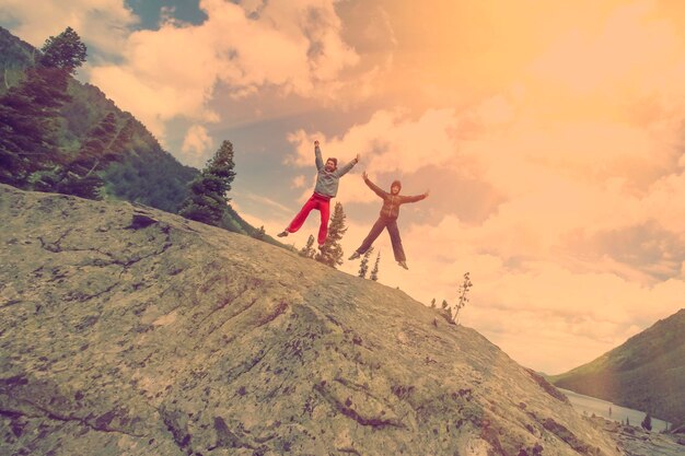 Two tourists in jumping with sun in background