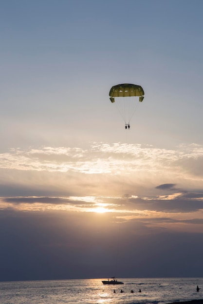 two tourists parasailing over the sea during sunset