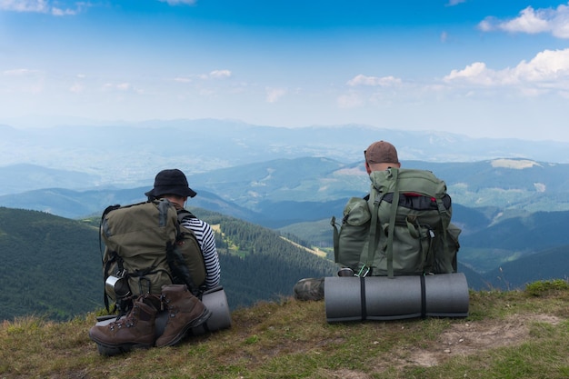 Foto due turisti seduti su una scogliera sullo sfondo delle montagne.