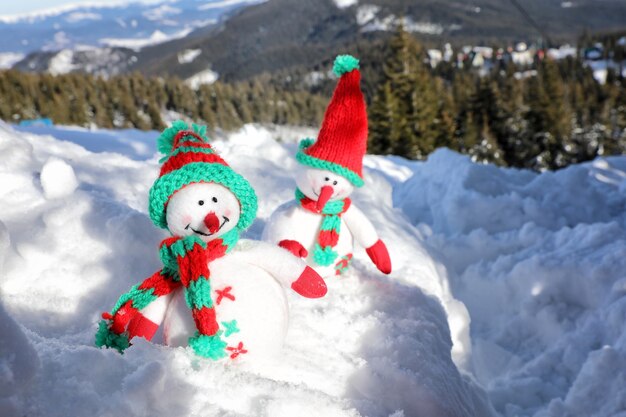 Two toy snowmen at mountain resort on sunny frosty day. Winter vacation