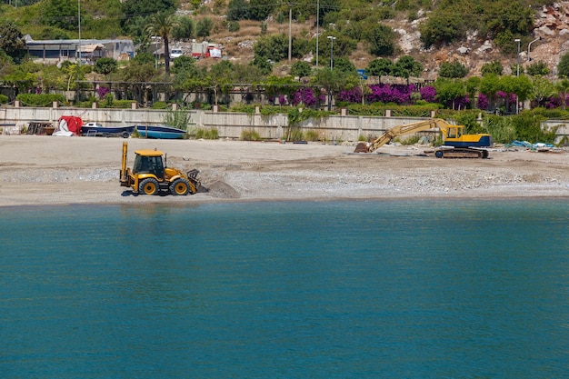 Two tractors on the beach take the beach sand in the buckets,Tractors on the beach