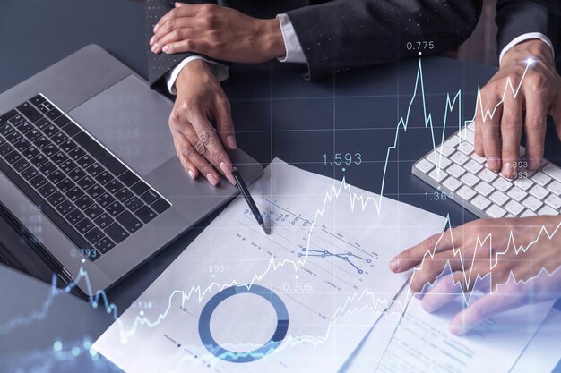 Two traders man and woman researching historic data to predict\
stock market behavior internet trading concept forex and financial\
hologram chart over the table with the documents