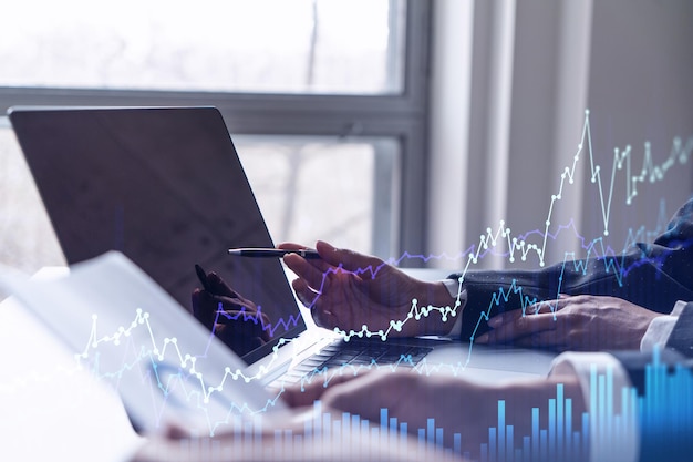 Photo two traders researching historic data to predict stock market behavior using laptop internet trading concept forex and financial hologram chart forecasting and planning