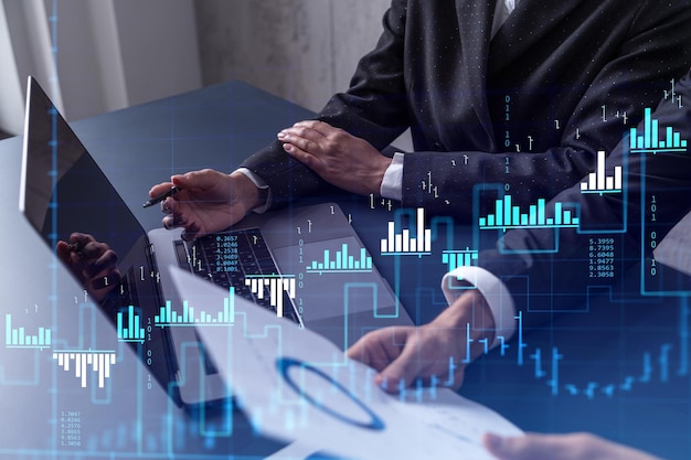 Two traders researching historic data to predict stock market behavior using laptop Internet trading concept Forex and financial hologram chart Forecasting and planning