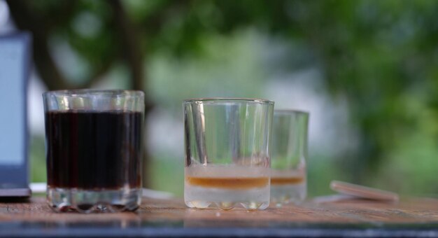 Photo two transparent glass glasses full of dark liquid and empty stand on table