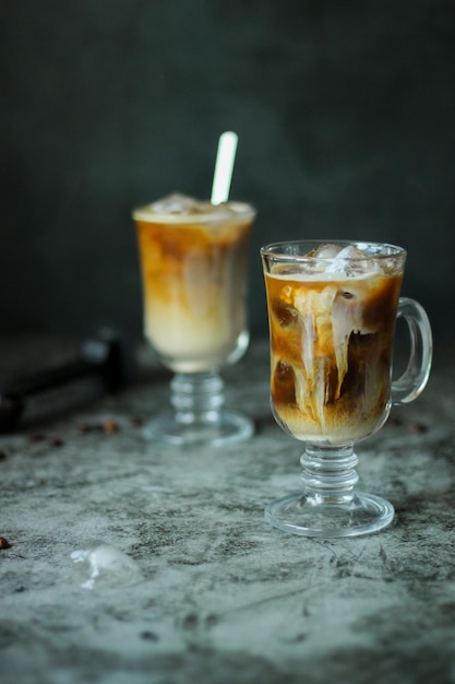 Two transparent glasses with a homemade black iced coffee and cold coffee and cream 