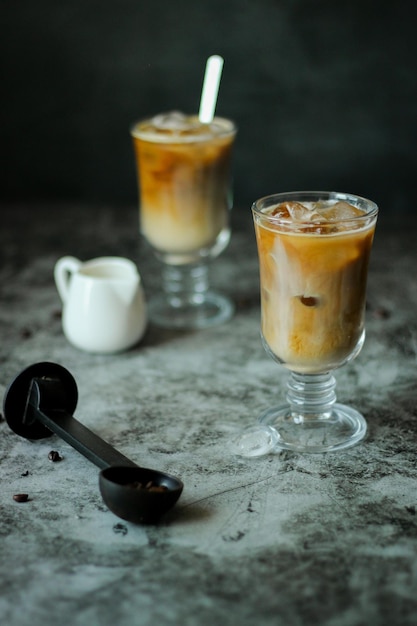 Two transparent glasses with homemade black iced coffee and cream - season drinks