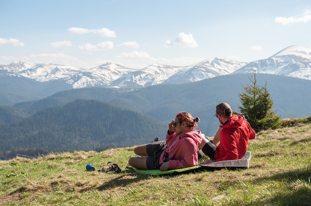 Two travelers are lying on sleeping bags on top 