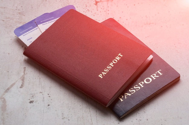 Photo two travelers passports red and blue with boarding passes for the plane.