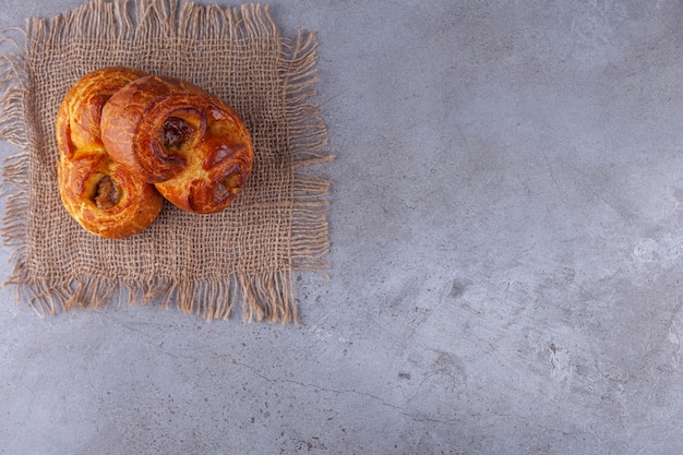 Two twirl fragrant pastries placed on stone background. 