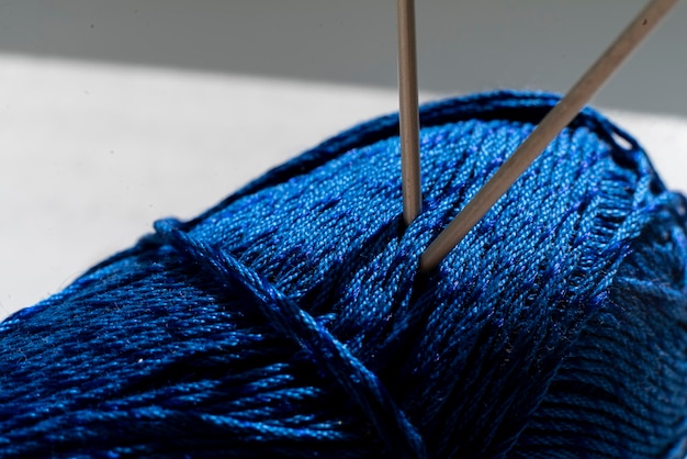 The two twisted knitting needles inserted in the yarn roll, macro view