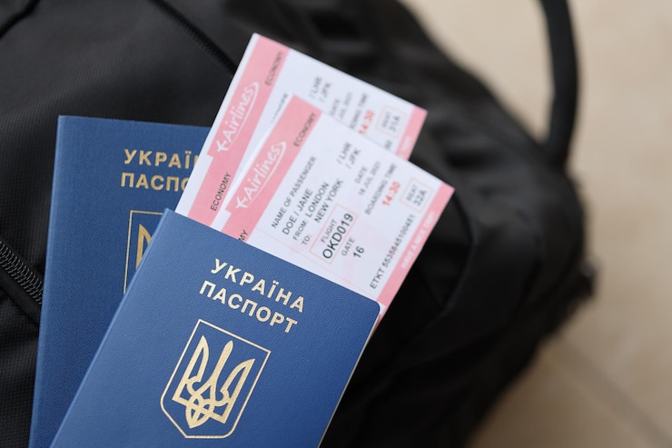 Фотография два украинских биометрических паспорта с авиабилетами на черном туристическом рюкзаке