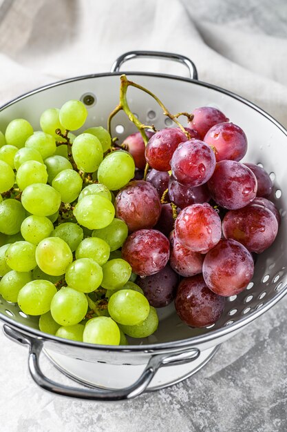 Two varieties of grapes, red and green in a colander. 