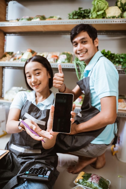 Two vegetable sellers showing the screen of a phone