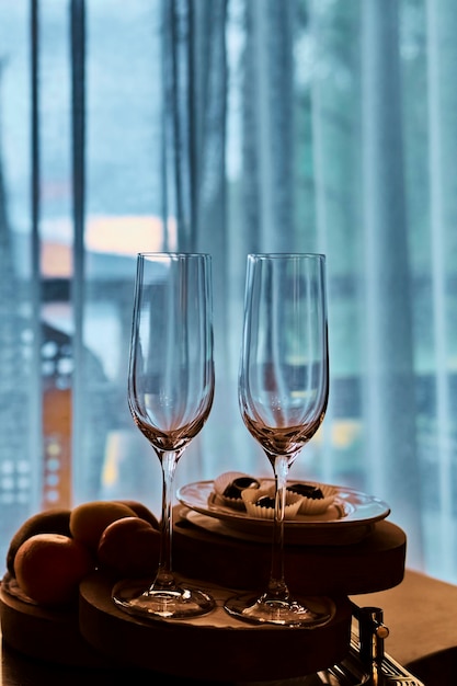 Two vine glasses standing on black tray against window.