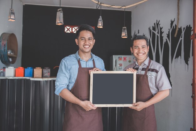 Two waiter holding blank blackboard