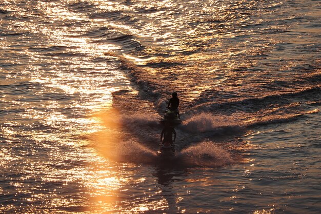 Two water scooter float on the water at sunset