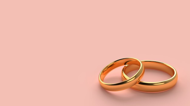 Два обручальных золотых кольца лежат друг на друге на фоне пустого пространства
