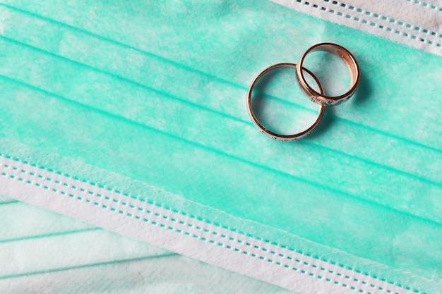 Two wedding rings lie on medical masks close-up. Quarantine wedding