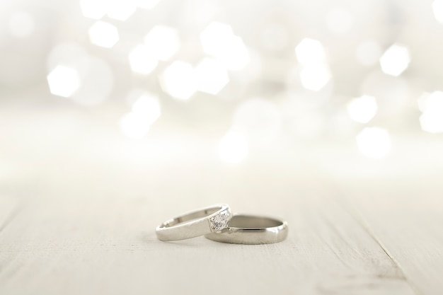 Два обручальных кольца на деревянном полу со светлым фоном боке
