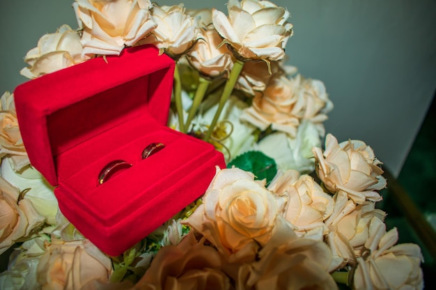 Two wedding rings in a red decorative box, on many flowers