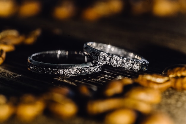 Two wedding rings with diamons laying on wooden surface