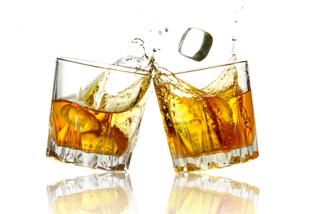 Two whiskey glasses clinking together, isolated