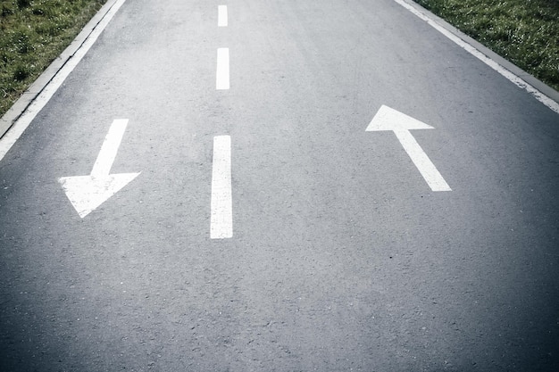 Two white arrow signs on opposite direction on asphalt road Both sides sign Up and Down arrows Direction for traffic safety way Pointer on gray asphalt floor