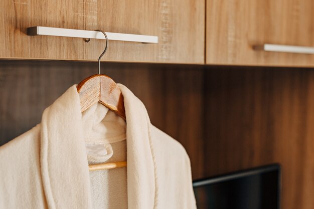 Two white bathrobes inside a cabinet with an open door and a TV niche