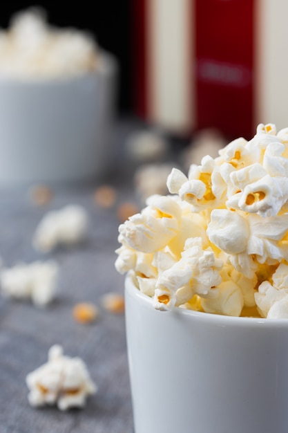 Two white bowls with popcorn on a blue wood.