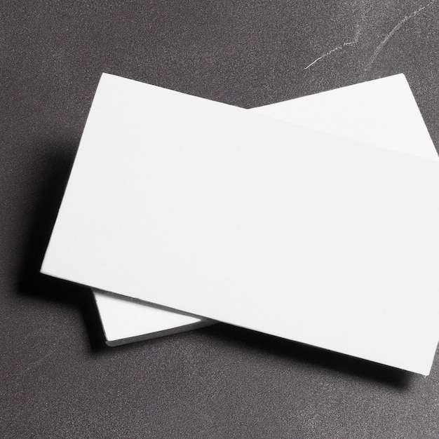 Two white business cards are laying on a black surface.