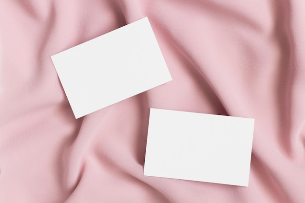 Two white business cards mockup on a soft pink textile 85x55mm